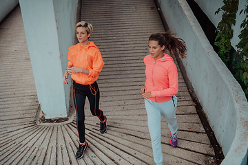 Image showing Two women in sports clothes running in a modern urban environment. The concept of a sporty and healthy lifestyle