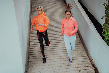 Image showing Two women in sports clothes running in a modern urban environment. The concept of a sporty and healthy lifestyle