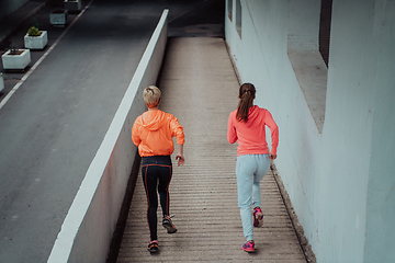 Image showing Two women in sports clothes running in a modern urban environment. The concept of a sporty and healthy lifestyle