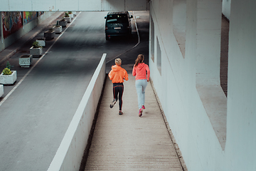 Image showing Two women in sports clothes running in a modern urban environment. The concept of a sporty and healthy lifestyle