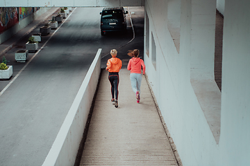 Image showing Two women in sports clothes running in a modern urban environment. The concept of a sporty and healthy lifestyle