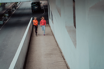 Image showing Two women in sports clothes running in a modern urban environment. The concept of a sporty and healthy lifestyle