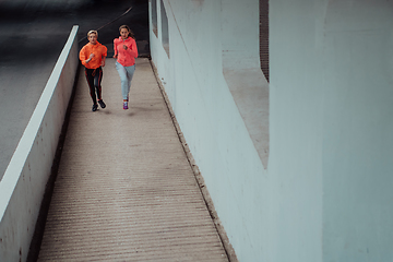 Image showing Two women in sports clothes running in a modern urban environment. The concept of a sporty and healthy lifestyle