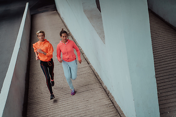 Image showing Two women in sports clothes running in a modern urban environment. The concept of a sporty and healthy lifestyle