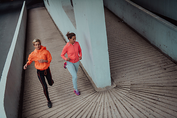 Image showing Two women in sports clothes running in a modern urban environment. The concept of a sporty and healthy lifestyle