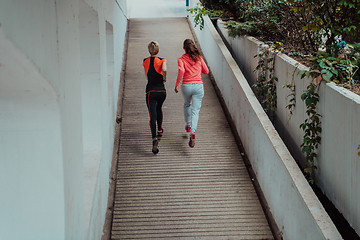 Image showing Two women in sports clothes running in a modern urban environment. The concept of a sporty and healthy lifestyle