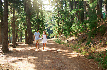 Image showing Walking, happy and a couple holding hands in nature for love, a date or holiday in Switzerland. Smile, care and a young man and woman on a walk in a forest, woods or mountains during a vacation