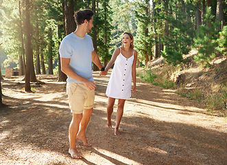 Image showing Nature, date and happy couple holding hands walking in a romantic forest or hiking adventure together in the woods. Explore, love and people or man and woman in a relationship walk outdoors in a park