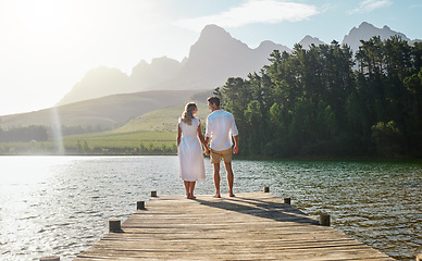 Image showing Love, couple and holding hands at lake, smile and bonding outdoors on vacation sunrise. Romance date, care and happy man and woman with trust, support or affection for romantic holiday at creek pier