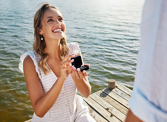 Image showing Happy, love and a woman proposing to a man, getting engaged and showing a ring. Couple, excited and a young girl asking her boyfriend for marriage, kneeling to propose and ask a question by a lake