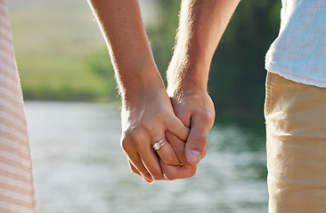 Image showing Holding hands, engagement and couple at lake outdoors for love, trust and support. Commitment, care and ring jewelry of woman and man together for romance, bonding or affection with soulmate at creek