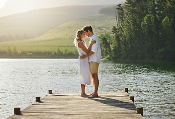 Image showing Couple, lake and engagement announcement of young people in love in nature. Happy, relax and hug of a woman and man together by water outdoor on summer vacation by a lakeside on holiday break