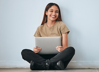 Image showing Portrait, smile and student woman with laptop in home for studying, learning or education. Technology, computer and happy female sitting on floor with pc for research on wall background for mockup.