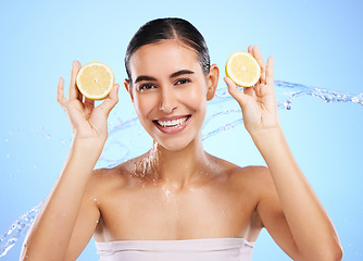 Image showing Health, lemon and water splash with portrait of woman in studio for natural cosmetics, nutrition and detox. Glow, fruits and hydration with female on blue background for diet, clean face and skincare