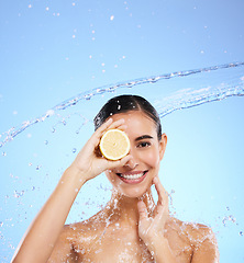 Image showing Spa, lemon and water splash with portrait of woman in studio for natural cosmetics, nutrition and detox. Glow, fruits and hydration with female on blue background for diet, clean face and skincare