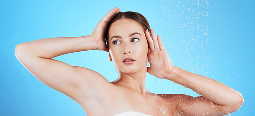 Image showing Shower, water and woman washing in studio for skincare, wellness and clean body for self care. Face of female aesthetic model, splash or drops for cleaning, hygiene and cosmetics on blue background