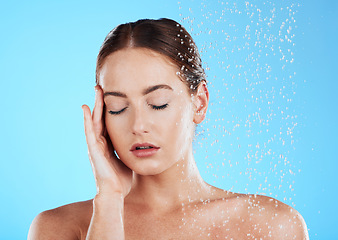 Image showing Shower, water and relax woman in a studio feeling happy from cleaning and skincare. Wellness, splash and beauty routine of a female model excited from dermatology and self care with blue background