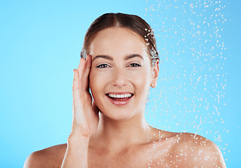 Image showing Shower, water and portrait of happy woman in a studio face from cleaning and skincare. Wellness, splash and beauty routine of female model excited from dermatology and self care with blue background