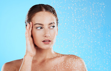 Image showing Shower, water and woman thinking in a studio feeling relax from cleaning or natural skincare. Wellness, wet or beauty routine of female model with facial dermatology and self care on blue background