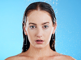 Image showing Shower, water and woman portrait in a studio with calm from cleaning and skincare. Wellness, face and beauty routine of female model in bathroom for dermatology and self care with blue background