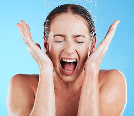 Image showing Shower, water and excited woman in a studio feeling happy from cleaning and skincare. Wellness, splash and beauty routine of model screaming with facial dermatology and self care with blue background