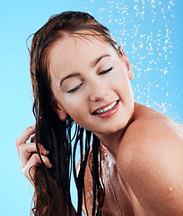 Image showing Shower hair care, water and woman in a studio feeling happy from cleaning and skincare. Wellness, splash and beauty routine of a female model with dermatology and shampoo wash with blue background