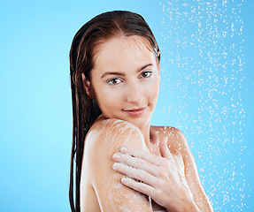 Image showing Shower, water and woman portrait in a studio relax from cleaning and skincare. Wellness, soap wash and beauty routine of a female model excited from dermatology and care with blue background