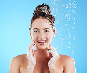 Image showing Hair care, shower and portrait of a female in a studio with a beauty, wellness and self care routine. Happy, smile and woman model washing her hair with shampoo and water isolated by blue background.