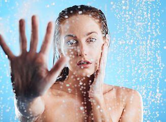 Image showing Shower portrait, water drops and woman hand doing skin cleaning, wellness and beauty routine in bathroom. Isolated, blue background and studio with young female doing hair care and dermatology facial