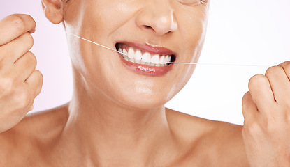 Image showing Face, smile and woman flossing teeth for cleaning, hygiene or tooth care in studio isolated on a purple background. Oral health, cosmetics and happy mature female model with dental floss for wellness