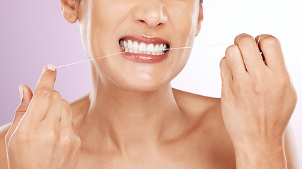 Image showing Face, woman and flossing teeth for cleaning, hygiene or tooth care in studio isolated on a purple background. Oral health, fresh breath or mature female model with dental floss or thread for wellness