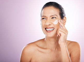 Image showing Face smile, cream and skincare of woman in studio isolated on a purple background. Mature, thinking and happy female model apply dermatology lotion, creme and moisturizer cosmetics for healthy skin.