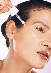 Image showing Face, skincare and woman with serum in studio isolated on a purple background. Dermatology, cosmetics and serious mature female model apply hyaluronic acid, retinol or essential oil for anti aging.