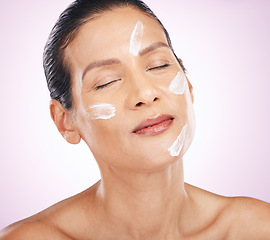 Image showing Face, cream and skincare of woman with eyes closed in studio isolated on a purple background. Mature, cosmetics and serious female model with dermatology lotion, creme or moisturizer for healthy skin