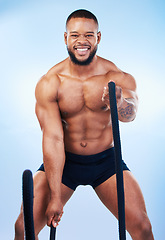 Image showing Fitness, man and portrait in battle rope for intense workout, exercise or training against blue studio background. Strong and fit muscular male model in roping practice for exercising endurance