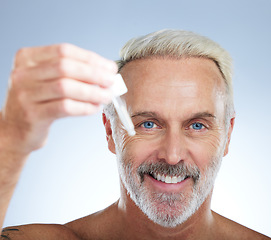 Image showing Old man, portrait and smile, face with serum for skincare, beauty and grooming with facial oil on studio background. Closeup of dropper, anti aging cosmetic care with happy senior male and hygiene