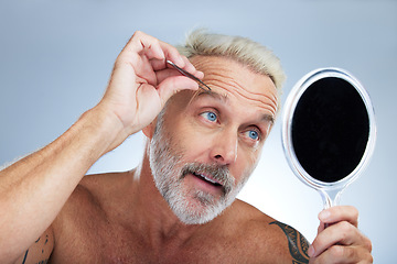 Image showing Senior man, tweezers and eyebrow in studio with mirror, grooming and self care for beauty by background. Model, check and tweezing for facial hair removal, cleaning and elderly cosmetics by backdrop