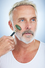 Image showing Senior man, jade roller and facial skincare with clean, self care and wellness in studio by white background. Elderly model, face skin massage or beauty with stone product, glow and dermatology detox