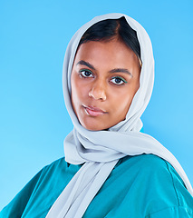 Image showing Muslim, serious woman and portrait with scarf on blue background, studio and backdrop. Young female model, islamic culture and beauty of empowerment, proud religion or arabic fashion of elegant hijab