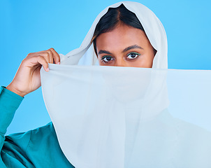 Image showing Muslim woman cover face with scarf in studio, blue background and color backdrop. Portrait, islamic female model and hijab for beauty, culture and confidence of religion, arabic fashion and style