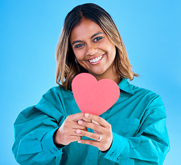Image showing Paper heart, happy woman and portrait in studio, blue background or backdrop. Smile, female model and shape of love, trust and support of peace, thank you and kindness on valentines day, date or hope