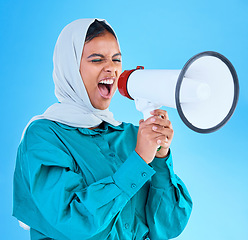 Image showing Young woman, muslim and megaphone in studio for protest, human rights and scream by blue background. Girl, islam and loudspeaker for speech, justice and vote for freedom, mission and power politics