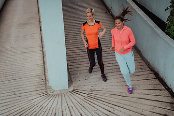 Image showing Two women in sports clothes running in a modern urban environment. The concept of a sporty and healthy lifestyle