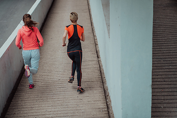 Image showing Two women in sports clothes running in a modern urban environment. The concept of a sporty and healthy lifestyle