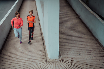 Image showing Two women in sports clothes running in a modern urban environment. The concept of a sporty and healthy lifestyle