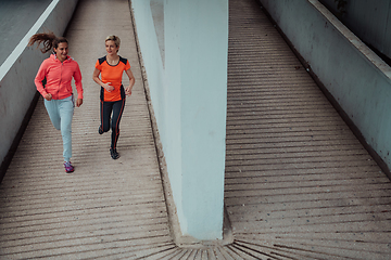 Image showing Two women in sports clothes running in a modern urban environment. The concept of a sporty and healthy lifestyle