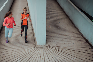 Image showing Two women in sports clothes running in a modern urban environment. The concept of a sporty and healthy lifestyle