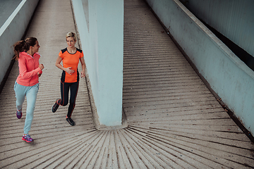 Image showing Two women in sports clothes running in a modern urban environment. The concept of a sporty and healthy lifestyle