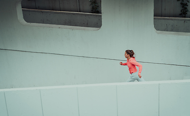 Image showing Women in sports clothes running in a modern urban environment. The concept of a sporty and healthy lifestyle