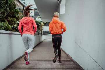 Image showing Two women in sports clothes running in a modern urban environment. The concept of a sporty and healthy lifestyle